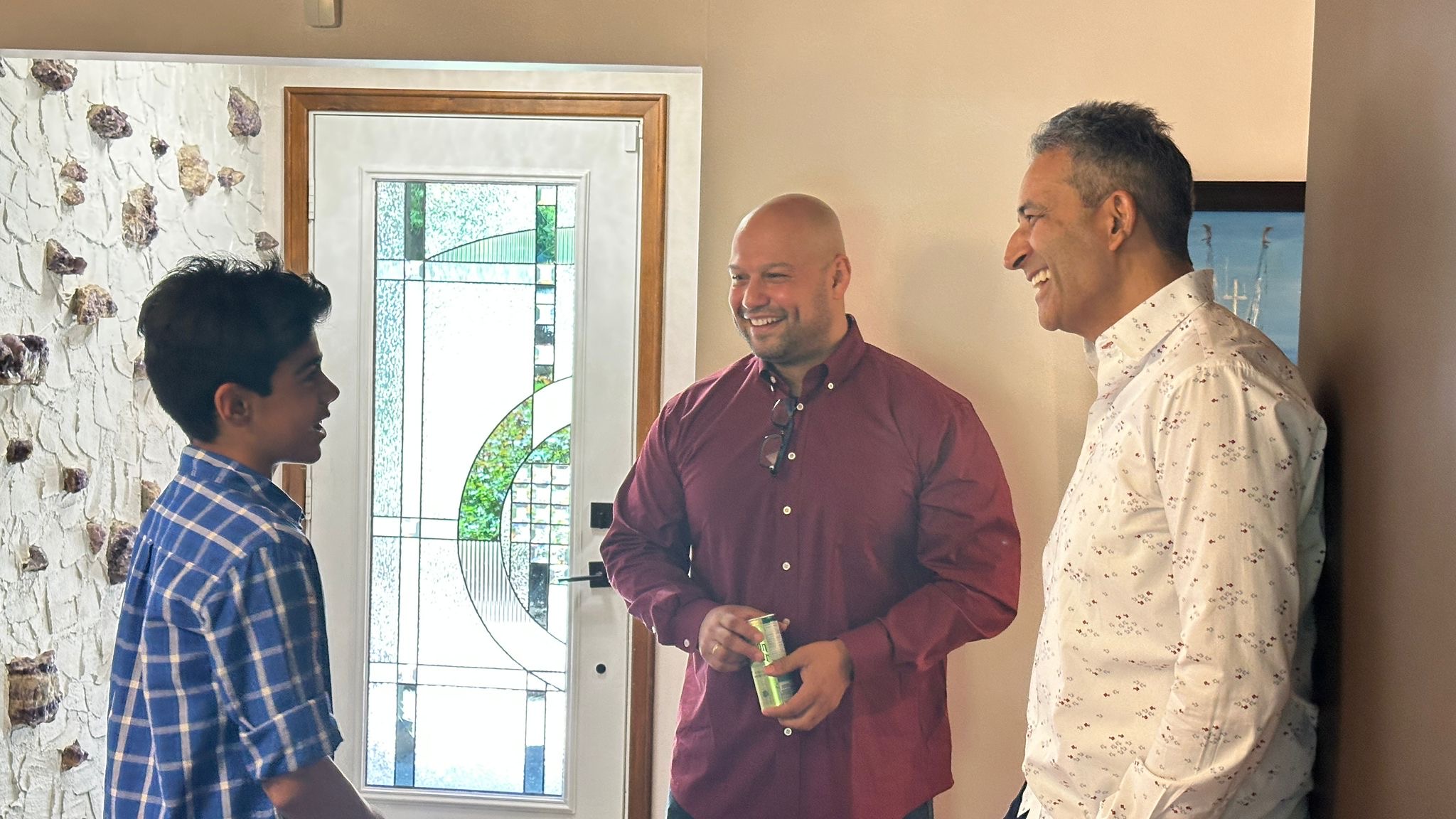 A young member sharing a laugh with two guests by the door